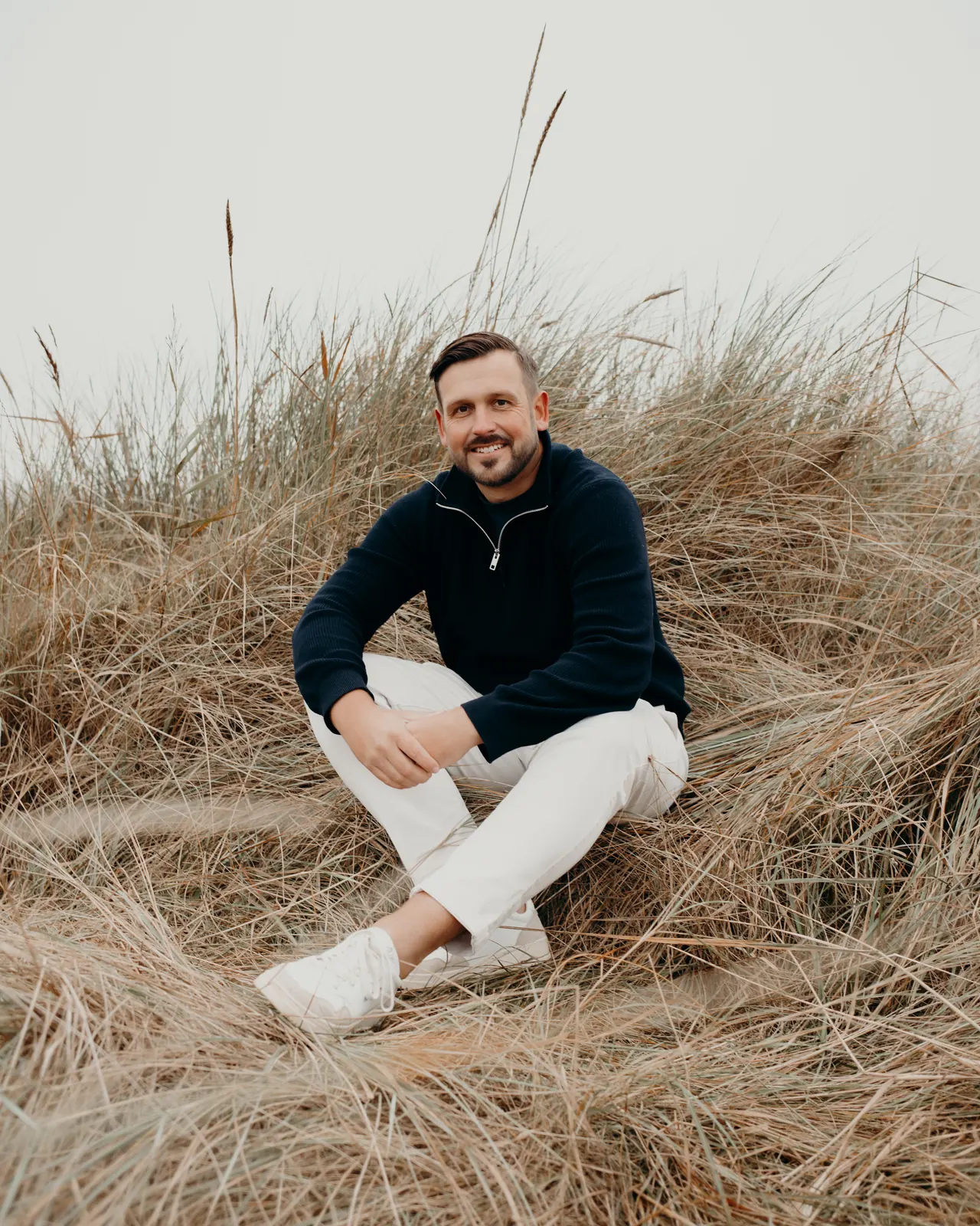 Collin Rettmer sitzt im Dünengras an der Nordseeküste